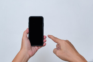 A man's hand pointing at a smartphone in his other hand