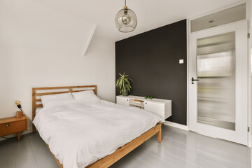 a bedroom with a bed, nightstand and mirror in the corner area on the left hand side of the room