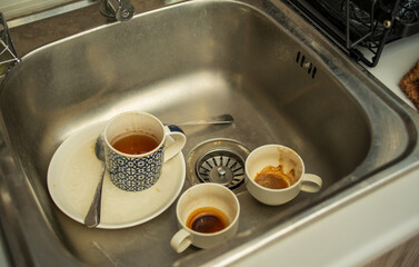 A collection of dirty glass and ceramic cups await their turn in the sink, ready for a much-needed...