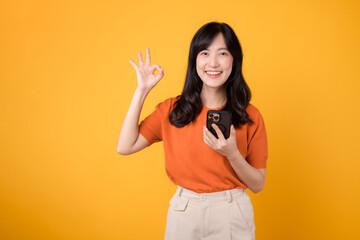 Spread happiness with a young Asian woman in her 30s, donning an orange shirt, showing okay hand...