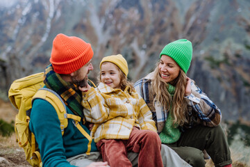 Happy family resting, having snack during hiking together in autumn mountains.