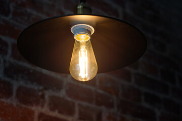 vintage electric lamp with a retro-style shade illuminates an old brick wall, loft