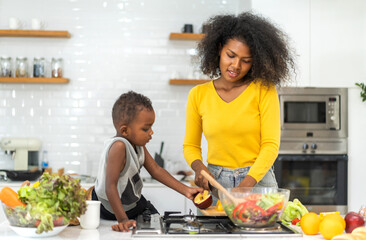 Portrait of enjoy happy love african american family mother and african little boy son child having fun help cooking food healthy eat together with fresh vegetable salad and ingredient in kitchen