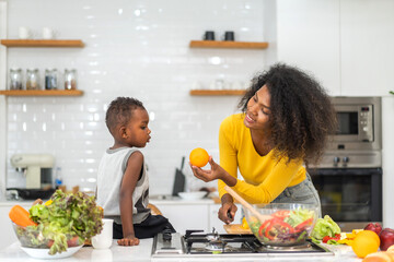 Portrait of enjoy happy love african american family mother and african little boy son child having fun help cooking food healthy eat together with fresh vegetable salad and ingredient in kitchen
