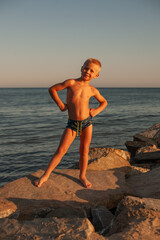 Fototapeta na wymiar Handsome boy posing on the seashore at sunset