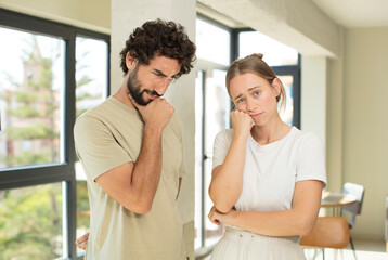Fototapeta premium young adult couple feeling sad and stressed, upset because of a bad surprise, with a negative, anxious look
