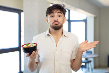 young handsome man shrugging, feeling confused and uncertain.  ramen japanese noodles concept