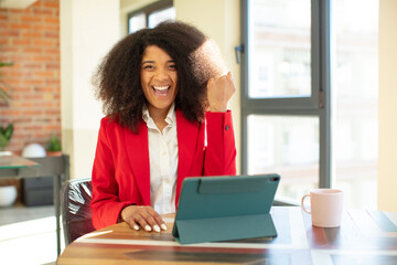 pretty afro black woman feeling shocked,laughing and celebrating success. businesswoman and laptop...