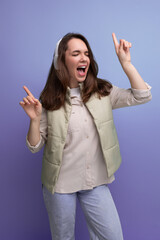 cheerful young lady brunette dances listening to music in headphones on a studio background