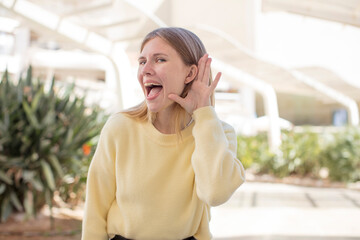 pretty young woman looking happy, listening, trying to hear a secret conversation or gossip,...