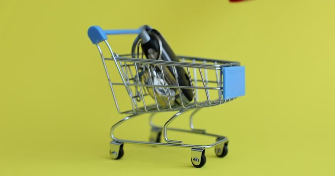 Closeup of car key with auto key fob inside basket on yellow background. Buying or renting car
