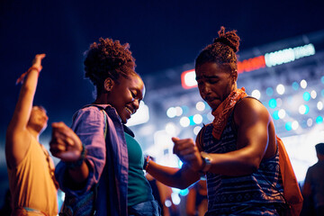 Young black couple dancing while enjoying in summer music festival at night.