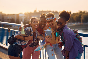 Multiracial group of happy friends taking selfie while going to summer music festival.