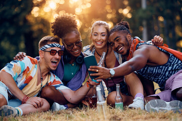 Multiracial group of happy festival goers taking selfie with mobile phone.