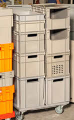 Plastic containers on a mobile wheeled trolley for warehouse work.