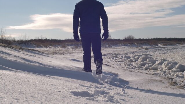 Man Walks in Snow on Remote Frozen Sea Beach on Sunny Winter Day Slow Motion