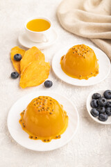 Mango and passion fruit jelly with blueberry on gray concrete, side view.