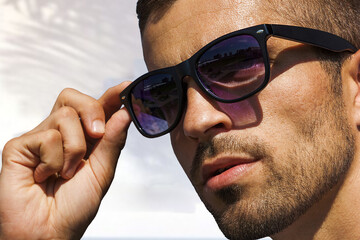 Unshaven man in sunglasses on the background of white architecture, eyewear advertising.