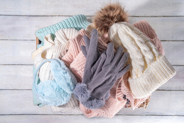 Preparation for fall and winter season, autumn warm cozy clothes, Stack of clean freshly laundered, neatly folded jackets, sweaters, blankets, hats, mittens in wooden box, taken from the mezzanine