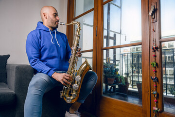 young latin man saxophonist playing jazz very inspired at home