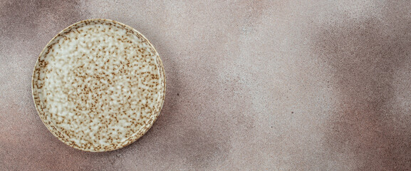 Empty ceramic plate with granite texture on a light background. Long banner format. top view