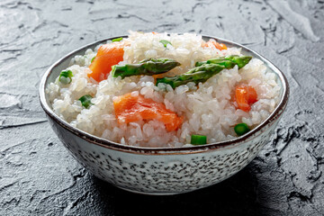 Konjac rice. Shirataki with salmon and asparagus, a healthy diet dish, on a black stone table