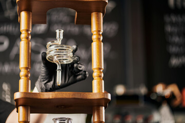 barista in black latex glove holding spiral part of cold brew coffee maker, alternative method