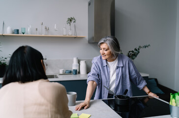 Smiling senior woman spending time in kitchen with young daughter