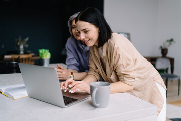 Content women messaging on laptop in modern office