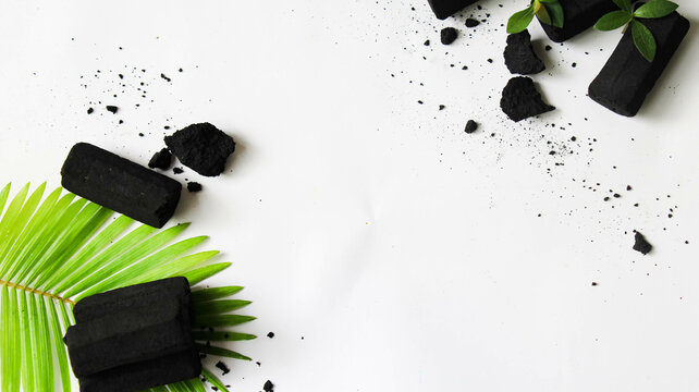 pile of charcoal with green leaf decoration on white isolated background