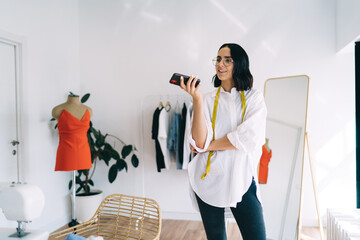 Smiling woman with smartphone in workshop