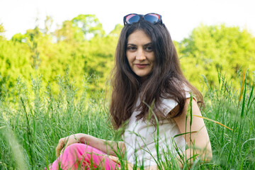 Portrait of a 35-year-old brunette woman looking at the camera smiling in nature.