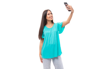 young european woman with dark long hair dressed in a blue loose-fitting t-shirt takes a selfie on the phone