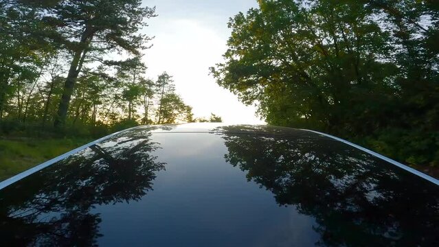 Self driving electric car driving on a country road surrounded by green trees. Green energy concept.