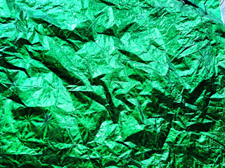 Beautiful abstract background and texture of crumpled aluminum foil in green color. Pattern, place for text, copy space