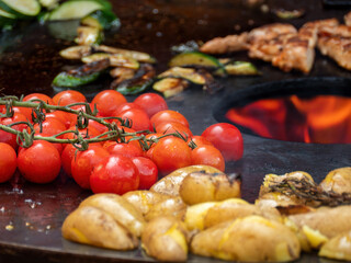 Obraz na płótnie Canvas Grilled Potatoes, Vine-Ripened Tomatoes, and Vegetables on the BBQ Grill