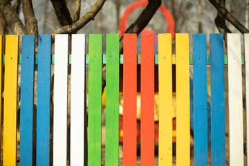 Cheerful fence made of colored boards. Fence in park. Creative design solution.