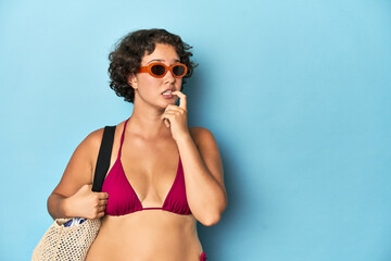 Young woman in bikini with beach bag relaxed thinking about something looking at a copy space.