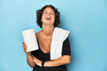 Young sportswoman with protein shake laughing and having fun.