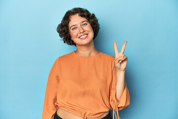Young Caucasian woman with short hair joyful and carefree showing a peace symbol with fingers.