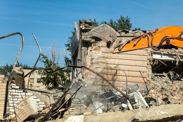 Fototapeta premium Excavator bucket raking the ruins house after the collapse.