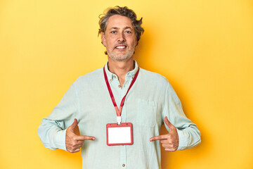 Man with an event ID card around his neck against a yellow backdrop.