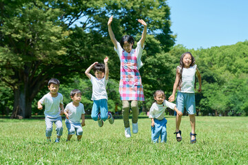 緑地でジャンプする子供たちと女性
