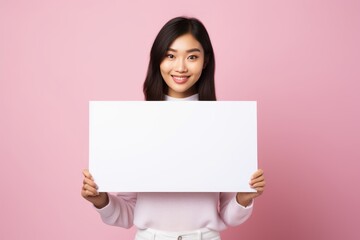 a beautiful asian woman holding a blank placard sign poster paper in her hands. empty space for editing and ads. isolated on pink pastel background. Generative AI