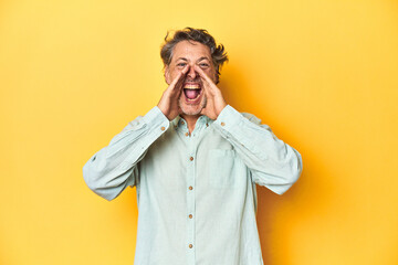 Middle-aged man posing on a yellow backdrop shouting excited to front.