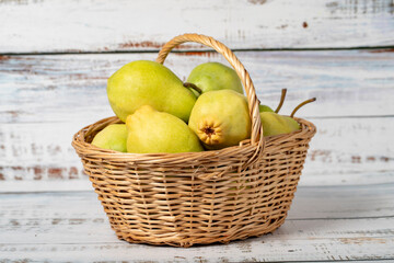 Fresh pears in a wicker basket over wooden background. Pear harvest season concept. Healthy and fresh fruit