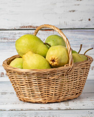 Fresh pears in a wicker basket over wooden background. Pear harvest season concept. Healthy and fresh fruit. Close up