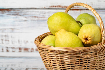 Fresh pears in a wicker basket over wooden background. Pear harvest season concept. Healthy and fresh fruit. Copy space. Empty space for text
