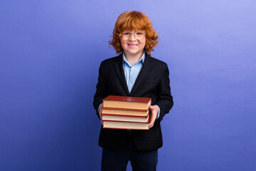 Photo of little intelligent person beaming smile arms hold pile stack book isolated on violet color background