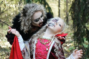 A woman in the form of a vampire or a sorceress bites a princess girl in fairy-tale makeup and...